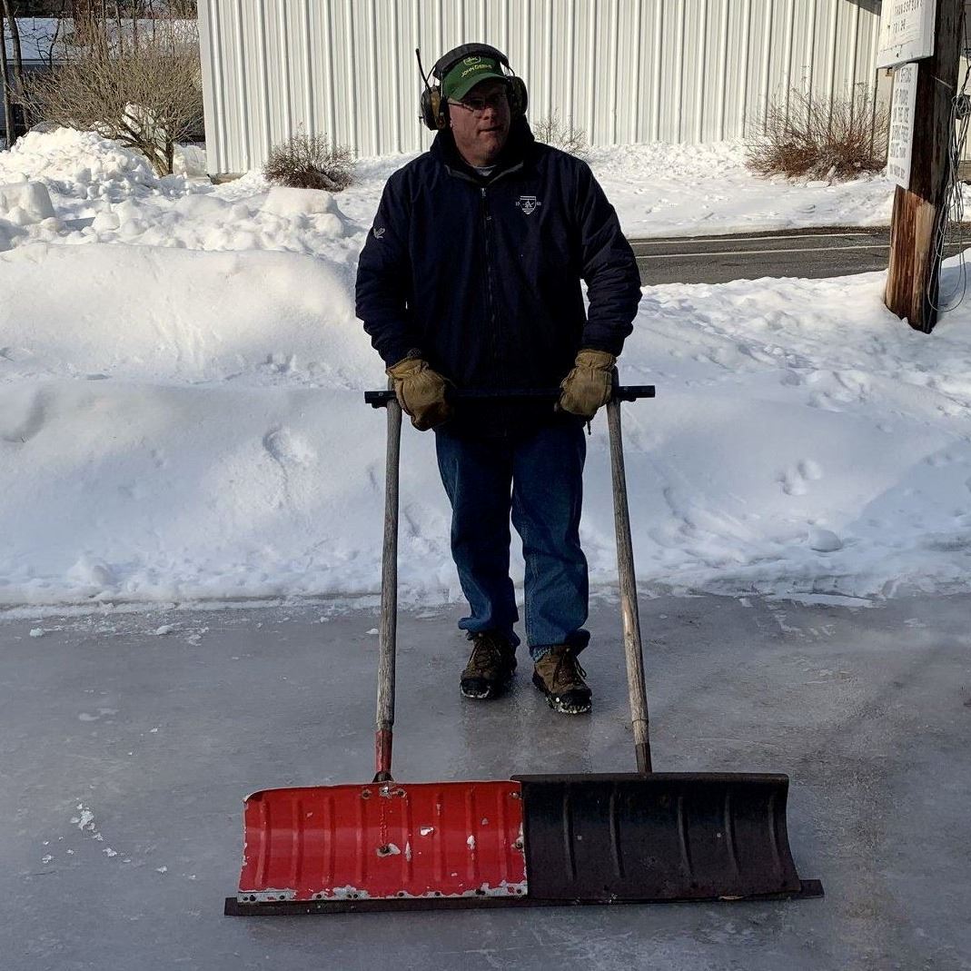 man standing on ice holding 2 shovels