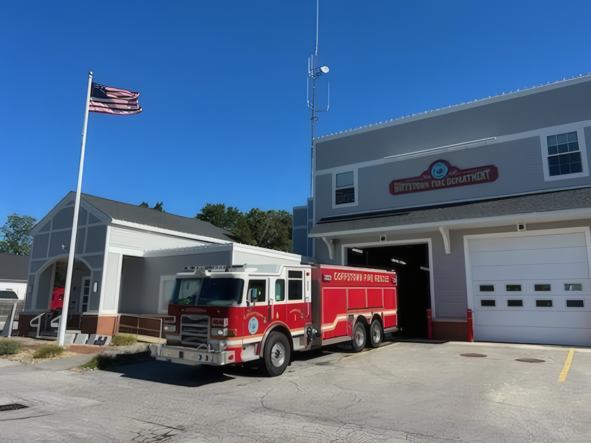 Fire Rescue Tanker 1 is parked outside a gray fire station with a white garage door.
