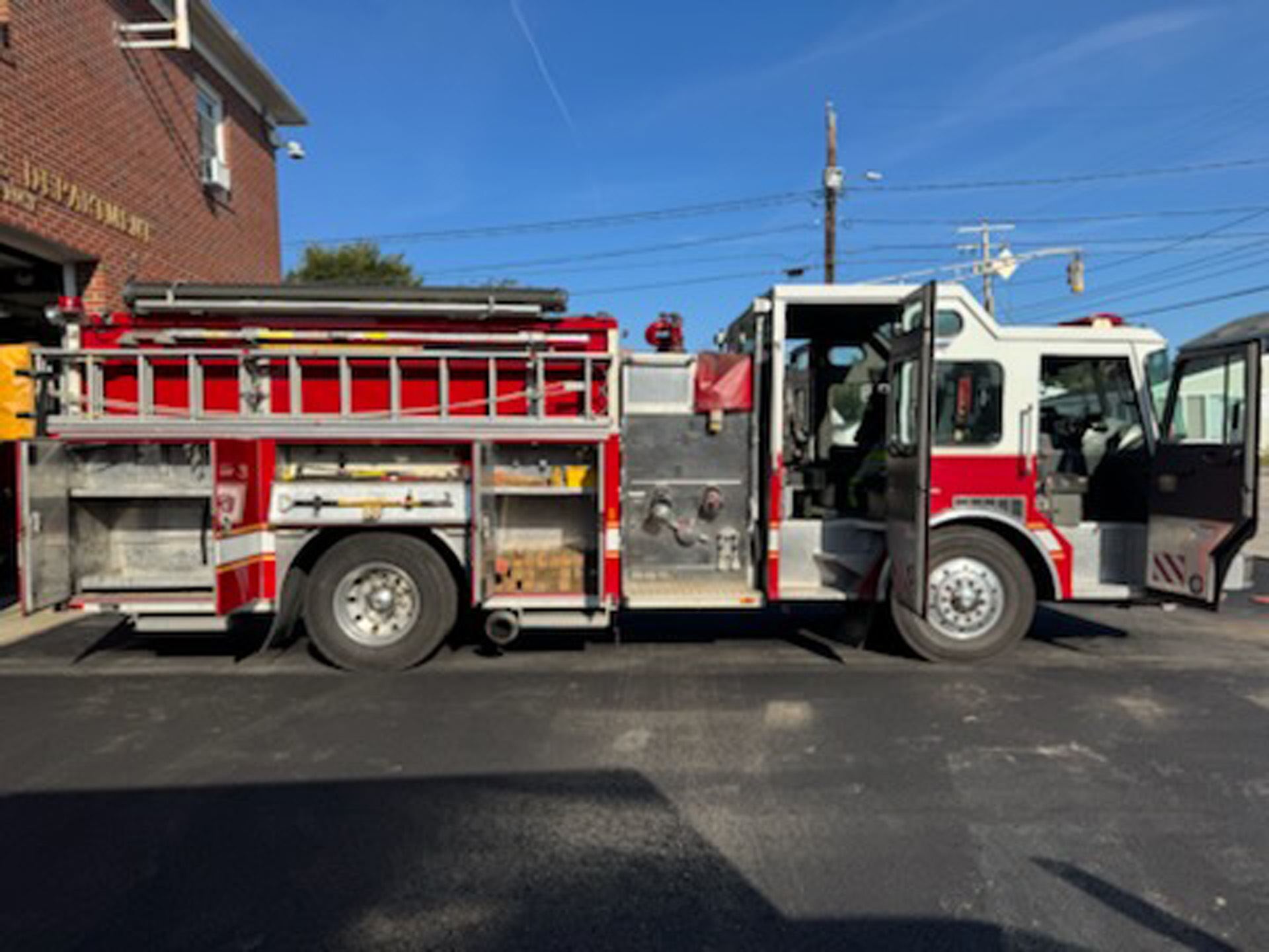 The curb side of the fire engine with compartments and doors open.
