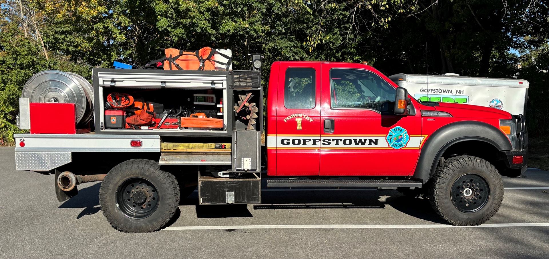 The passenger side of the forestry truck with open compartments showing equipment.